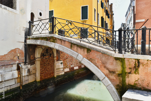 Vintage bridge in the city of Venice over a water canal. Colourful buildings in the background