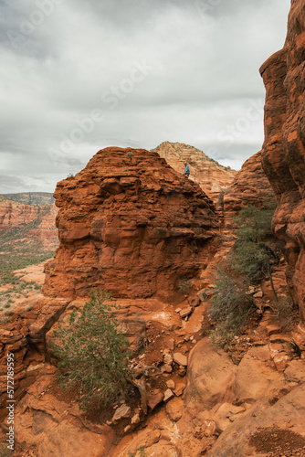 Man hiker standing on Bell Rock with incredible views within coconino national forest in Sedona Arizona USA against white cloud background.