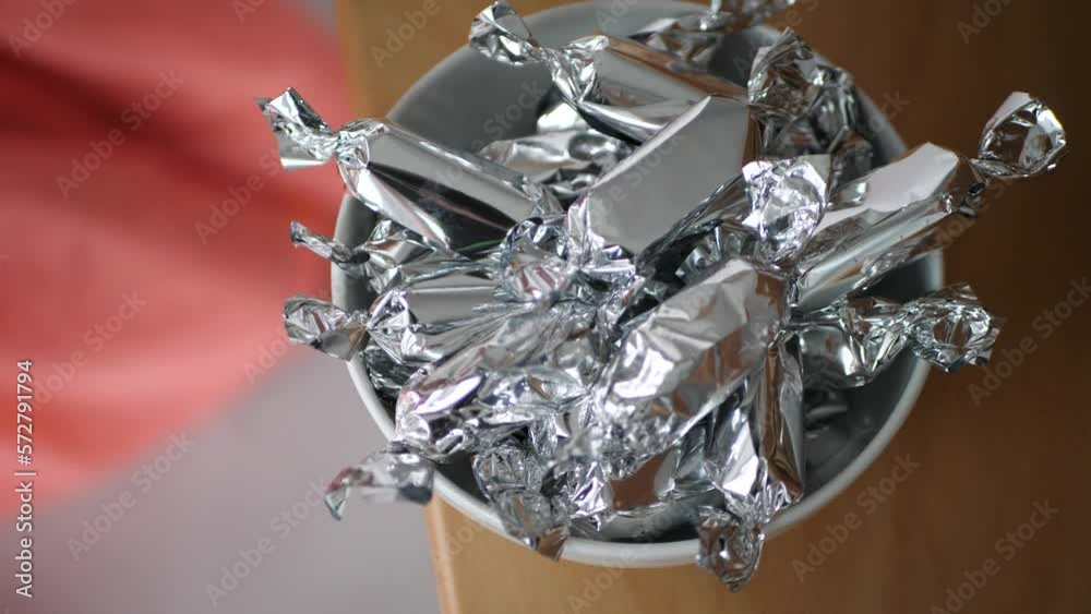 Candy wrapped in silver paper falling into a bowl Candy wrapped in silver paper falling into a bowl
