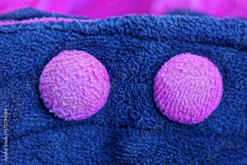 two large purple buttons on blue fabric on clothes