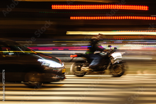 car and motorcycle on a city street at night © Christian Müller