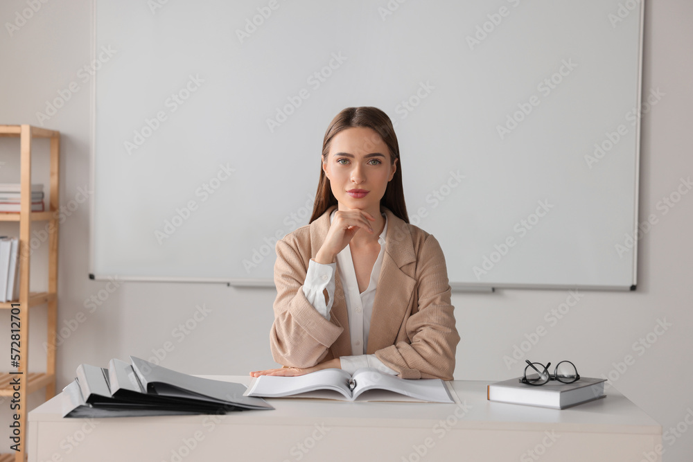 Young teacher sitting at table in classroom Young teacher sitting at table in classroom