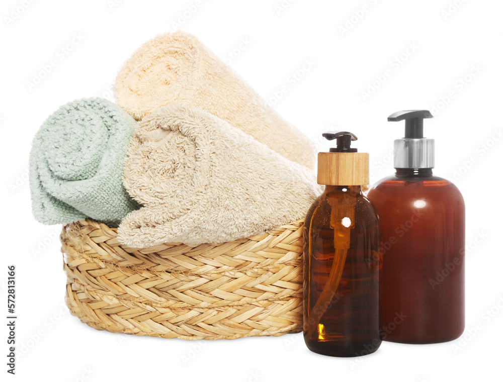 Soft towels in wicker basket and bottles of cosmetic products on white background Soft towels in wicker basket and bottles of cosmetic products on white background