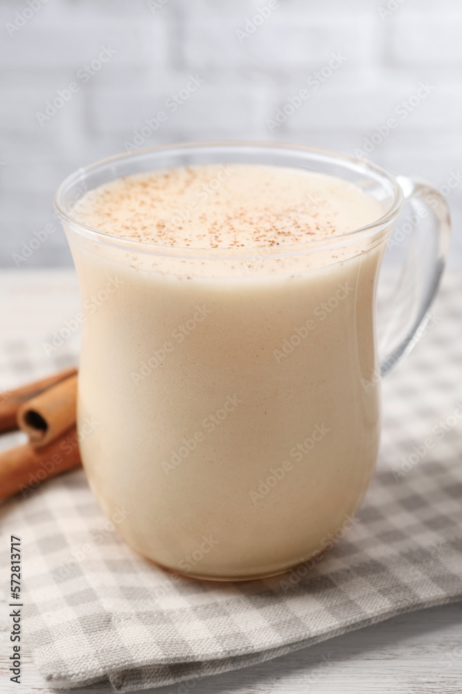 Delicious eggnog with cinnamon on wooden table, closeup Delicious eggnog with cinnamon on wooden table, closeup