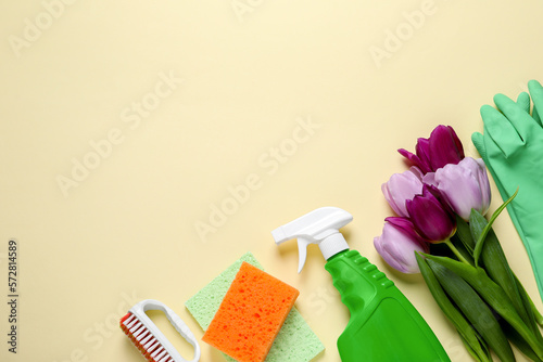 Spring cleaning. Detergent  flowers  brush  sponge and rag on beige background  flat lay. Space for text