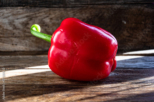 Ripe red bell pepper on a wooden kitchen table.