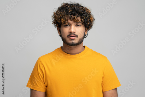 Young Indian bearded man looking confidently at camera over isolated gray background
