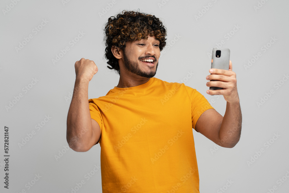 Smiling Asian student holding phone, clenching fist from happiness while passing exams to university Smiling Asian student holding phone, clenching fist from happiness while passing exams to university