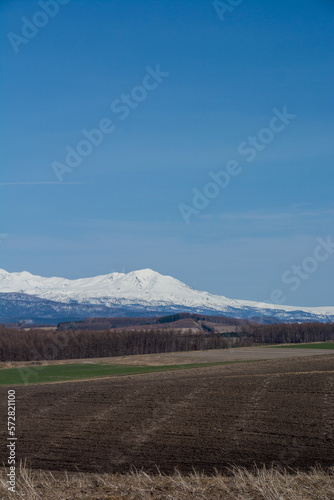 晴れた春の日の畑作地帯と雪山 大雪山 