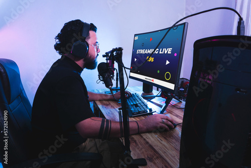 Professional hispanic gamer with headphones and a microphones making a streaming live.