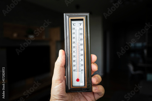 hand with a plastic mercury thermometer shows the temperature in room. Powerful heating in Russia. 22 degrees Celsius is the norm for the temperature in an apartment in Russia in winter.