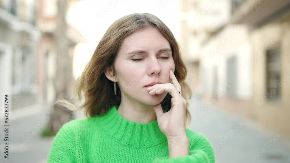 Young blonde woman standing with doubt expression at street