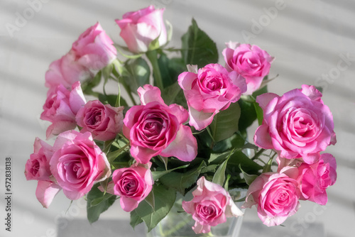 The photo shows a bouquet of pink roses in a vase