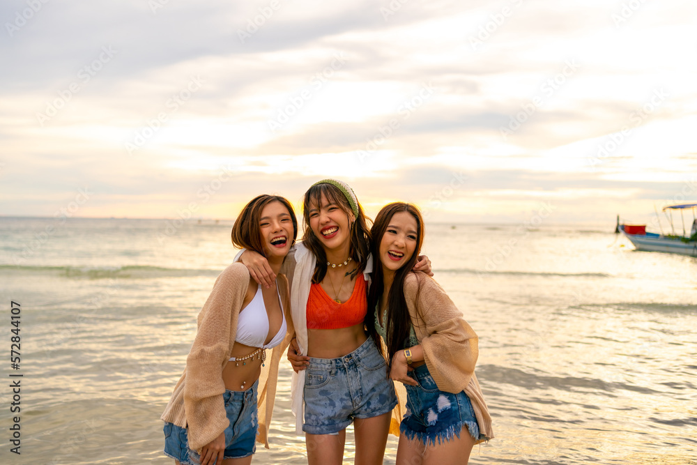 Portrait Group of Young Asian woman friends in walking and playing together on tropical island beach at summer sunset. Attractive girl enjoy and fun outdoor lifestyle travel on beach holiday vacation.