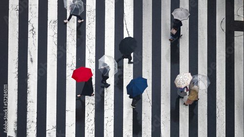 Obraz na plátne Crowd of busy pedestrian people holding umbrella crossing street crosswalk in Tokyo City, Japan in autumn raining day