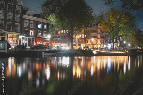 Amsterdam canal, bridge, and medieval houses in the evening, Bright cityscape of Amsterdam with night lights reflection in the water, Night landscape with houses and canal in amsterdam