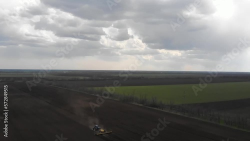 Blue tractror planting sunflower with yellow planter on the cultivated field in Ukraine photo