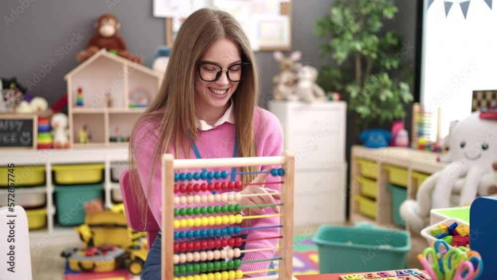 Young blonde woman preschool teacher teaching maths with abacus at kindergarten