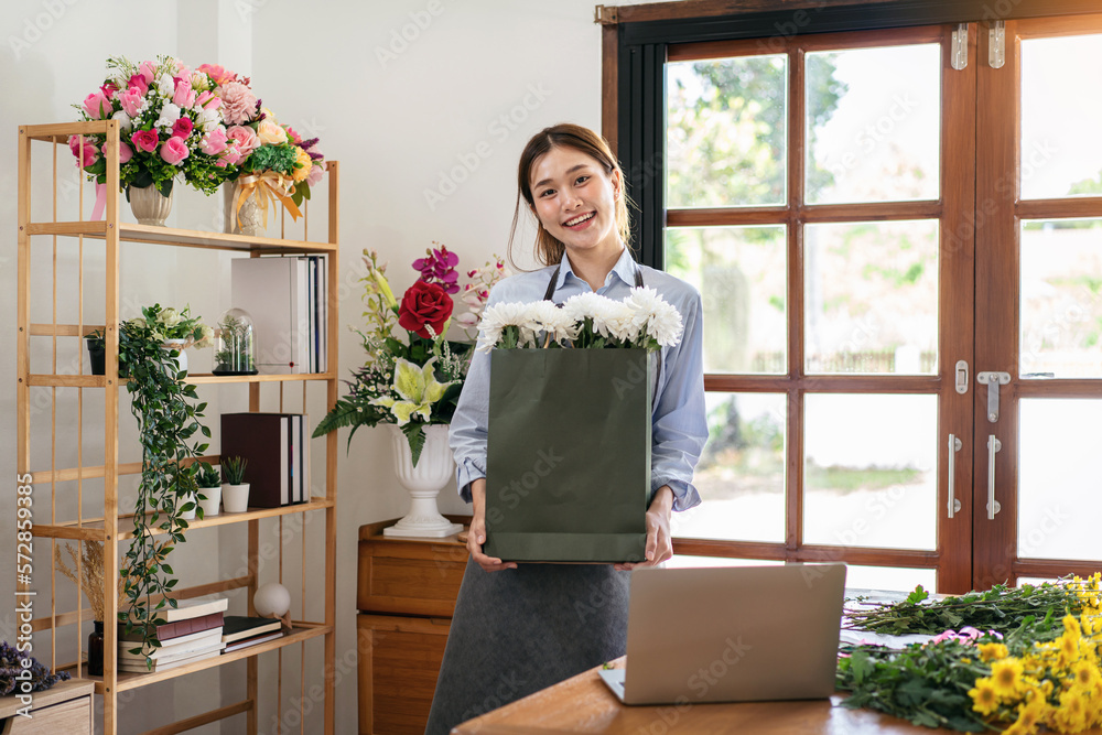 Female florist in apron holding paper bag of white chrysanthemum Female florist in apron holding paper bag of white chrysanthemum
