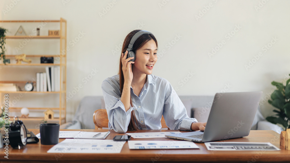 Female freelance is using laptop and wearing headphone to meetin Female freelance is using laptop and wearing headphone to meetin