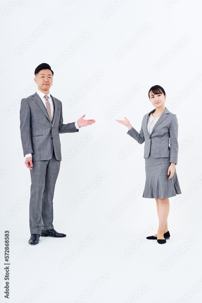 案内のポーズをするスーツ姿の男女 案内のポーズをするスーツ姿の男女