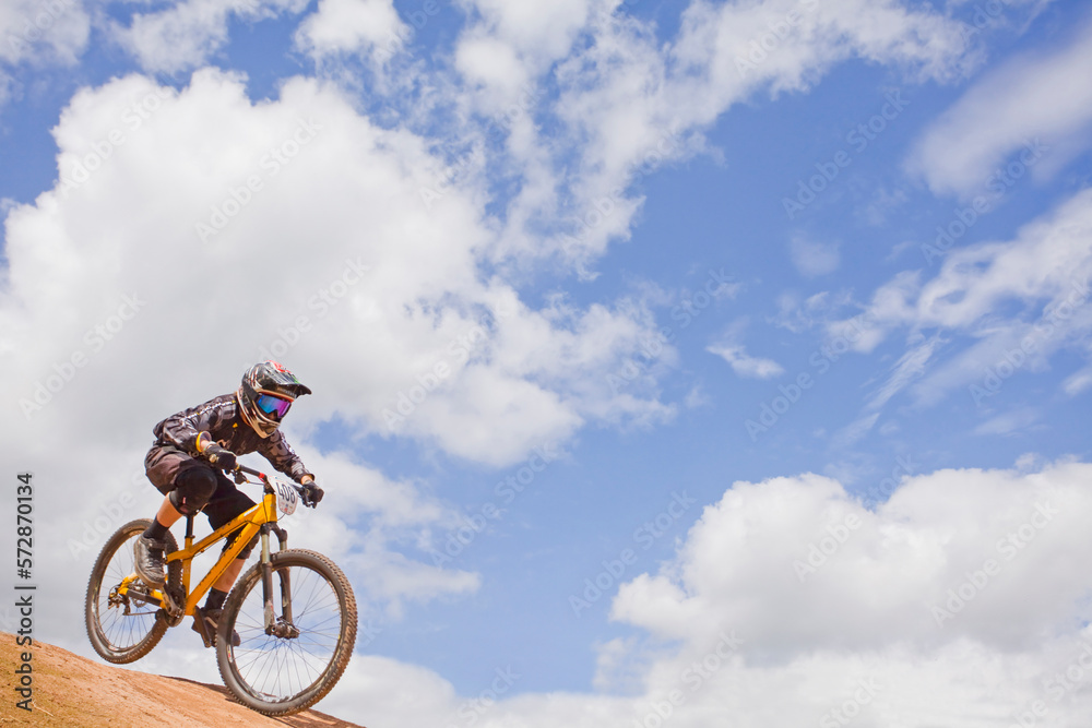 Man in full face helmet riding mountain bike, blue skies 4X race,UK Man in full face helmet riding mountain bike, blue skies 4X race,UK