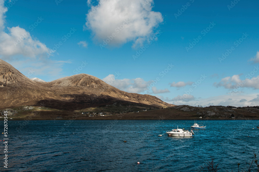 Boats anchored in blue waters of Isle of Skye near Cuillin mountain range, Scotland, UK Boats anchored in blue waters of Isle of Skye near Cuillin mountain range, Scotland, UK