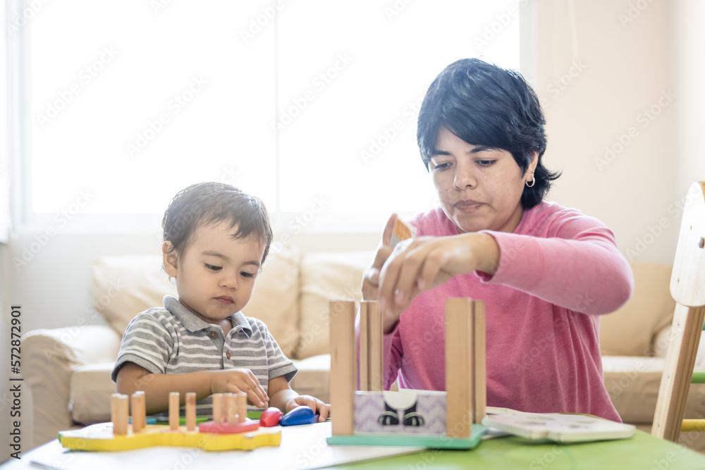Latin mother and little son playing together with wooden logic toys. Latin mother and little son playing together with wooden logic toys.