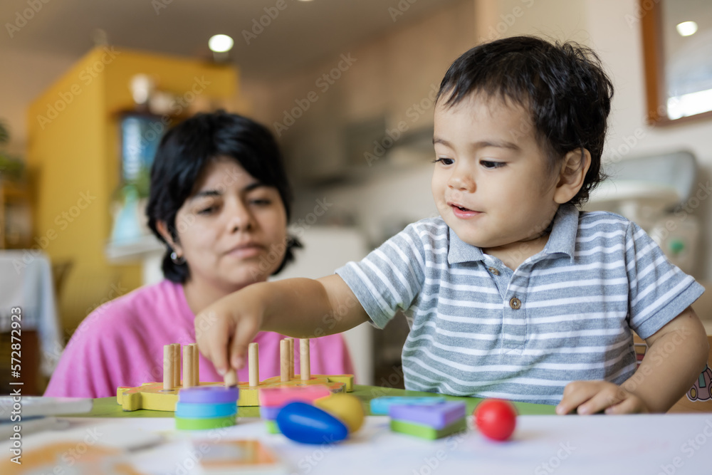 Latin mother and little son playing together with wooden logic toys. Latin mother and little son playing together with wooden logic toys.