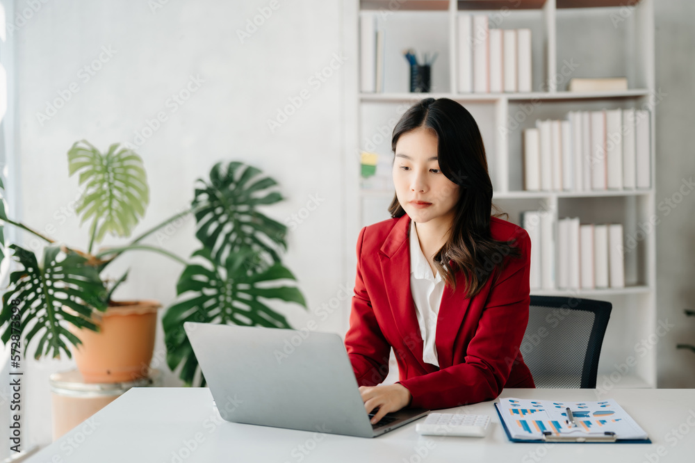 Confident business expert attractive smiling young woman typing laptop ang holding digital tablet on desk in creative office.. Confident business expert attractive smiling young woman typing laptop ang holding digital tablet on desk in creative office..