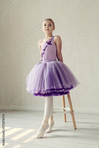 Tableau sur toile portraits ballerina girl in a lilac dress posing in a room showing ballet poses