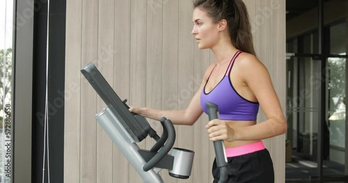 Sporty woman on elliptical trainer in the gym