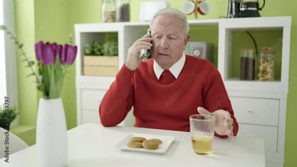 senior eating cookies and drinking juice speaking on the phone at home senior eating cookies and drinking juice speaking on the phone at home