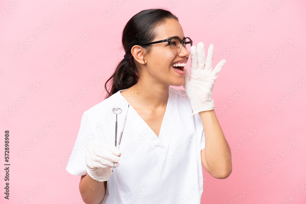 Dentist Colombian woman isolated on pink background shouting with mouth wide open to the side Dentist Colombian woman isolated on pink background shouting with mouth wide open to the side