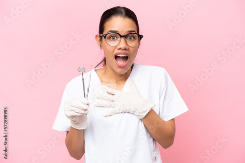Dentist Colombian woman isolated on pink background surprised and shocked while looking right