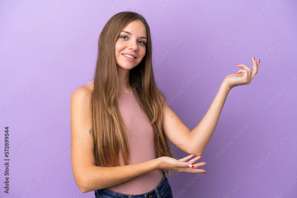Young Lithuanian woman isolated on purple background extending hands to the side for inviting to come Young Lithuanian woman isolated on purple background extending hands to the side for inviting to come