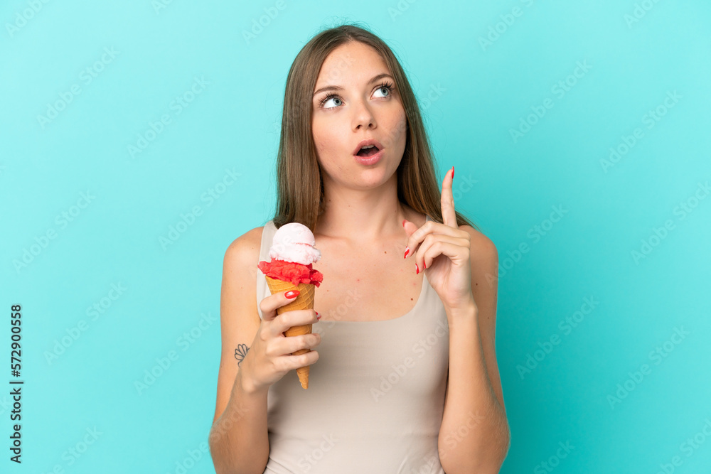 Young Lithuanian woman with cornet ice cream isolated on blue background thinking an idea pointing the finger up