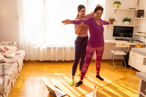 The daughter explains to her mother how to do the exercise. Pretty  business woman doing sport exercise at home, watching tutorials on a laptop. How to keep fit indoors