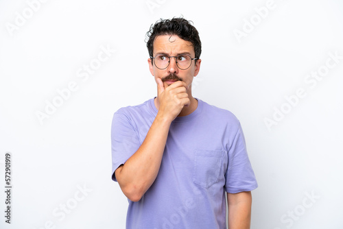 Young man with moustache isolated on white background having doubts and with confuse face expression