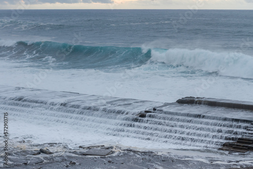 Stormy sea waves crashing and creating white foam against small fishermen's pier in Punta del Hidalgo, Tenerife, Canary Islands. Spain