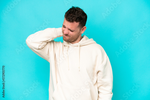 Young caucasian handsome man isolated on blue background with neckache © luismolinero