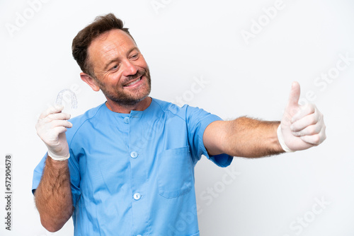 Middle age dentist man holding envisaging isolated on white background giving a thumbs up gesture