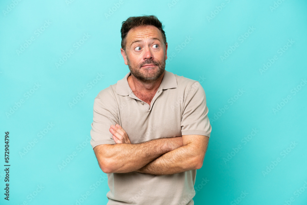 Middle age caucasian man isolated on blue background making doubts gesture while lifting the shoulders Middle age caucasian man isolated on blue background making doubts gesture while lifting the shoulders