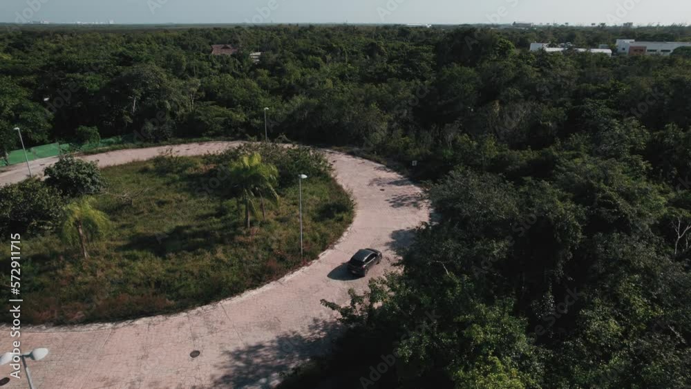 Top down aerial view to a car driving in roundabout. Automobile in green landscape. Top down aerial view to a car driving in roundabout. Automobile in green landscape.