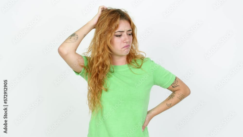 Young redhead woman having doubts while scratching head over isolated background Young redhead woman having doubts while scratching head over isolated background