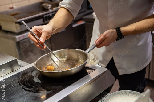man chef cooking fried shrimp in frying pan on kitchen