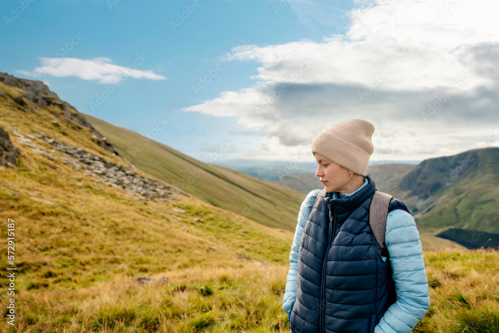 Woman reaching the destination and on the top of mountain against cloudy blue sky on autumn day Travel Lifestyle concept The national park Lake District in England Woman reaching the destination and on the top of mountain against cloudy blue sky on autumn day Travel Lifestyle concept The national park Lake District in England