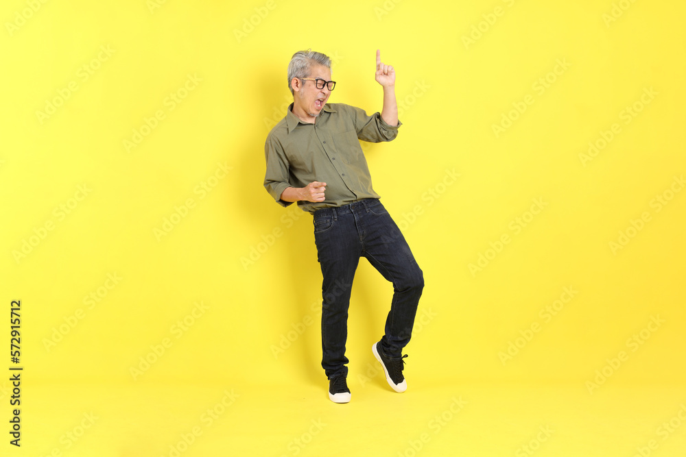 The 40s adult Asian man with casual dressed standing on the yellow background. The 40s adult Asian man with casual dressed standing on the yellow background.