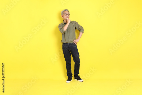 The 40s adult Asian man with casual dressed standing on the yellow background.