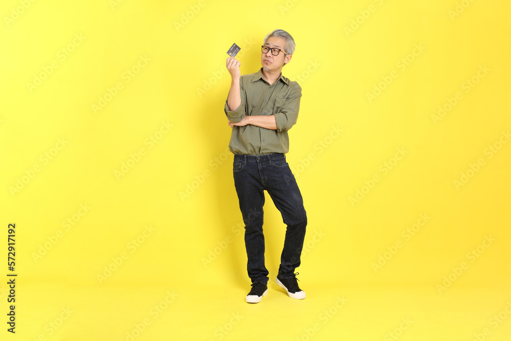 The 40s adult Asian man with casual dressed standing on the yellow background. The 40s adult Asian man with casual dressed standing on the yellow background.
